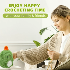 Detail of a handmade green crochet dinosaur plush toy with orange horns and white belly