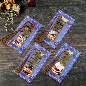 Set mit vier hohlen Metall-Lesezeichen mit bunten Designs und Quasten auf Holzgrund