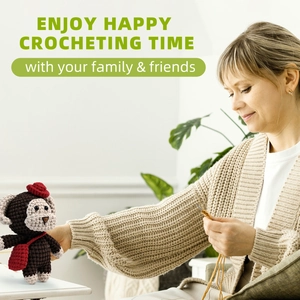 Close-up of a person crocheting a cute brown monkey doll with a red hat and bag