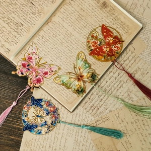 Vista de marcadores de mariposa metálicos con borlas coloridas sobre libros antiguos