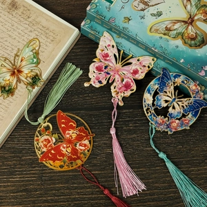 Detalle de cuatro marcapáginas de mariposa metálicos con diseño calado y borlas largas de seda