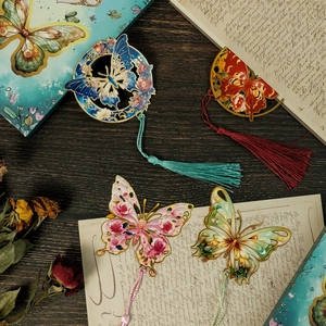 Detalle de cuatro marcapáginas de mariposa en metal calado con elegantes borlas de seda