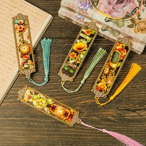 Close-up of four vintage hollow metal bookmarks with retro motifs and colorful silk tassels
