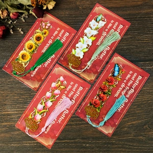 Set of four floral metal hollow bookmarks with colorful tassels on a vintage wood desk