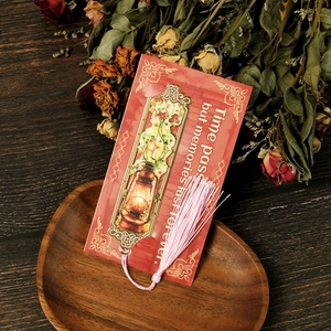 Detail of vintage metal bookmark with kerosene lamp design and soft pink tassel