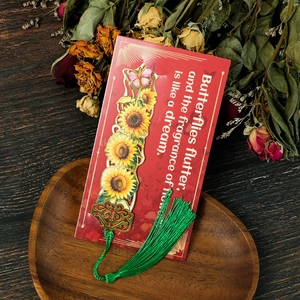 Detail of sunflower metal bookmark with green tassel and butterfly on wood tray