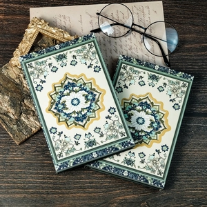 Detail of vintage mandala patterned notebooks on a rustic wooden desk with glasses