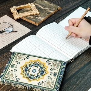 Detail of vintage mandala notebook with grid paper pages and elegant wooden desktop props