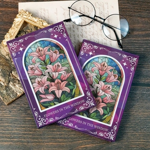 Detail von zwei Hardcover Notizbüchern mit Buntglas Lilien-Design auf dem Tisch