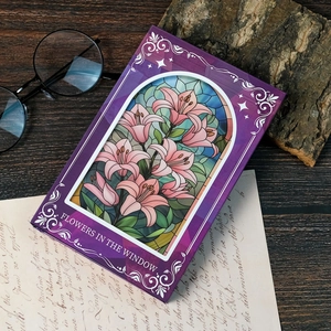 Detailaufnahme eines lila Notizbuchs mit buntem Lilien-Design im Kirchenfenster-Stil