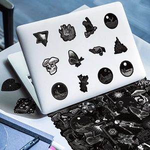 Detail of dark gothic graffiti stickers on white laptop including skull and cat art