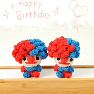 Cute red and blue crochet clown dolls on a wooden stand for handmade birthday gift