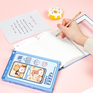 Close-up of cute blue cartoon puppy notebook with lined pages on pink background