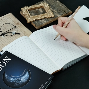 Close-up of starry moon notebook with lines and inspirational quote for daily writing