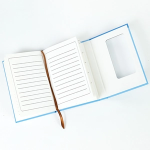 Close-up of blue notebook with lined pages, silk bookmark, and back cover card slot
