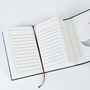 Macro shot of starry sky notebook with moon-shaped cutout and dotted grid pages