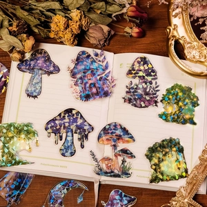 Detail of laser iridescent PET mushroom stickers on a vintage notebook with dried flowers