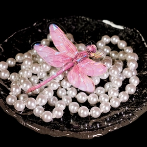 Detailansicht eines rosa PET-Libellenaufklebers mit Goldfolie auf Perlenschmuck-Hintergrund