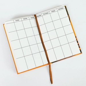 Detail view of monthly planner inner pages with orange hard cover and brown ribbon