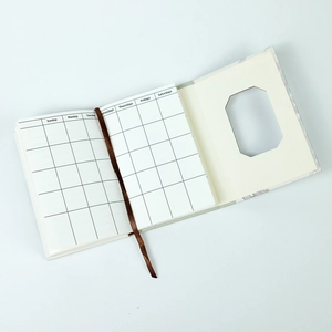 Detail of trifold planner showing grid layout, silk bookmark, and octagonal window cutout