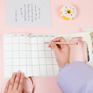 Close-up of a grid planner page with a wooden pencil on a soft pink background