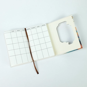 Detail of portable tri-fold notebook with monthly grid pages and a brown silk bookmark
