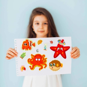 Close-up of a child holding colorful marine ocean life DIY mix and match sticker sheets