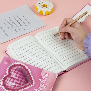 Detail of pink notebook with heart cutout and 3D textured pink plaid heart pattern