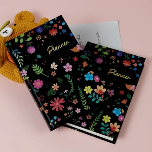Planner floreali creativi con scritte dorate su un delicato sfondo rosa tenue