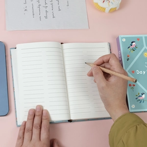 Close-up of mint green Daydream series notebook with hand-drawn bird and floral illustrations