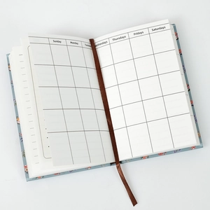 Detail of floral daily planner with monthly grid pages and a brown silk ribbon bookmark