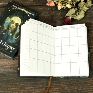 Detail view of fairy-themed hardcover notebook showing daily grid pages and silk bookmark