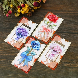 Set of four elegant rose metal bookmarks in red, blue, purple, and pink on wood