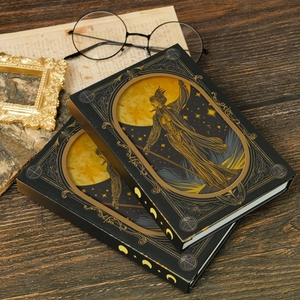 Macro shot of two vintage tarot notebooks with gold moon phase illustrations on wood surface