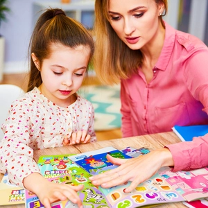 Close-up of mother and child interacting with educational animal sticker book for learning