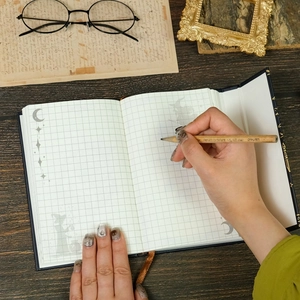 Dettaglio del taccuino a tema mago con pagine a quadretti e icone magiche vintage