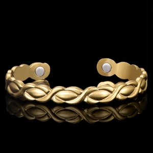 Macro view of rose gold magnetic therapy cuff with woven texture and mirror reflection