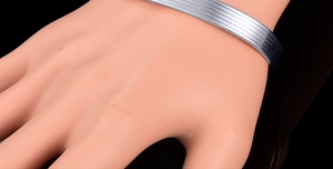 Detail of silver plated magnetic therapy cuff bracelet with five horizontal grooves on wrist