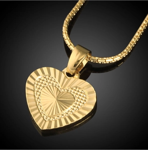 Macro shot of a 18K gold plated heart pendant with sunburst texture on black mirror
