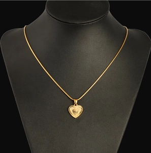 Detail of 18K gold plated heart pendant with sunburst texture on black neck model