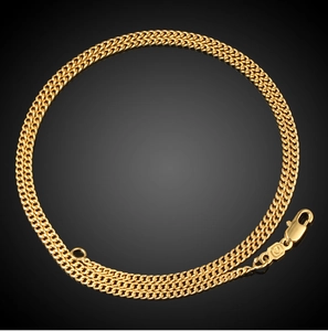Macro detail of 18K gold plated Figaro chain necklace with lobster clasp closure