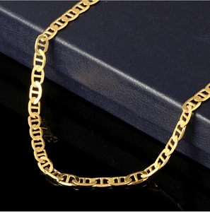 Close-up of 18K gold plated marina chain links on a dark textured jewelry box