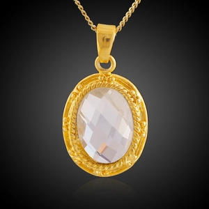 Macro shot of gold-plated oval pendant featuring clear crystal with braided border