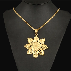 Macro view of a 18K gold-plated sunflower pendant on a wheat chain over a black bust