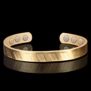 Detail view of 18K gold plated cuff bracelet with engraved grid texture and inner magnets