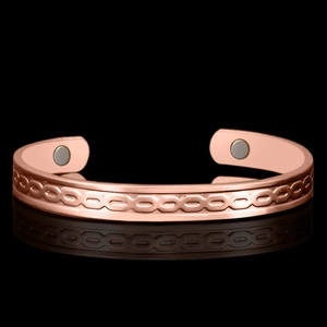 Macro view of rose gold magnetic therapy cuff bracelet with embossed chain patterns
