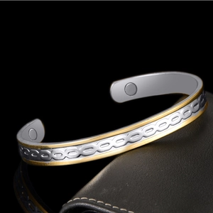 Two-tone gold and silver magnetic therapy open bangle with circular pattern on dark leather