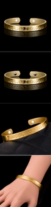 Detail showing 18K gold-plated magnetic cuff bracelet with embossed zodiac patterns