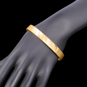 Bracciale rigido aperto placcato oro 18K con strisce diagonali su modello a mano nera