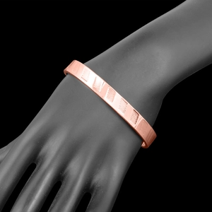 Rose gold magnetic open bangle for women with textured geometric relief on black display